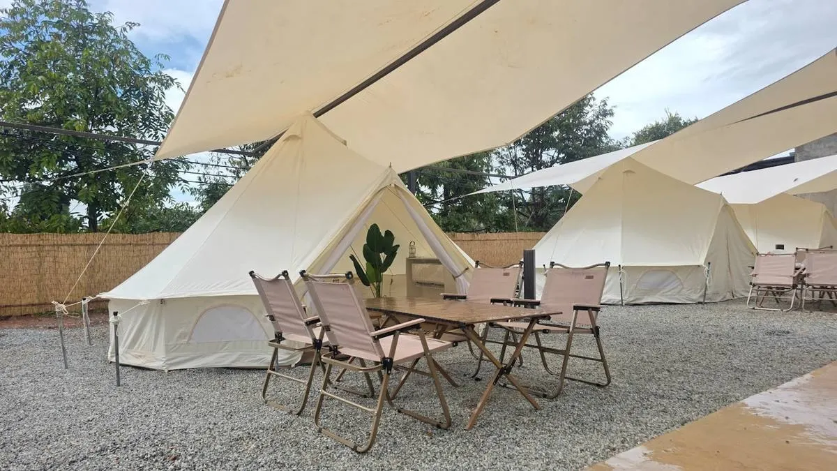 Bell tent Pool View dengan meja dan kerusi kayu di luar