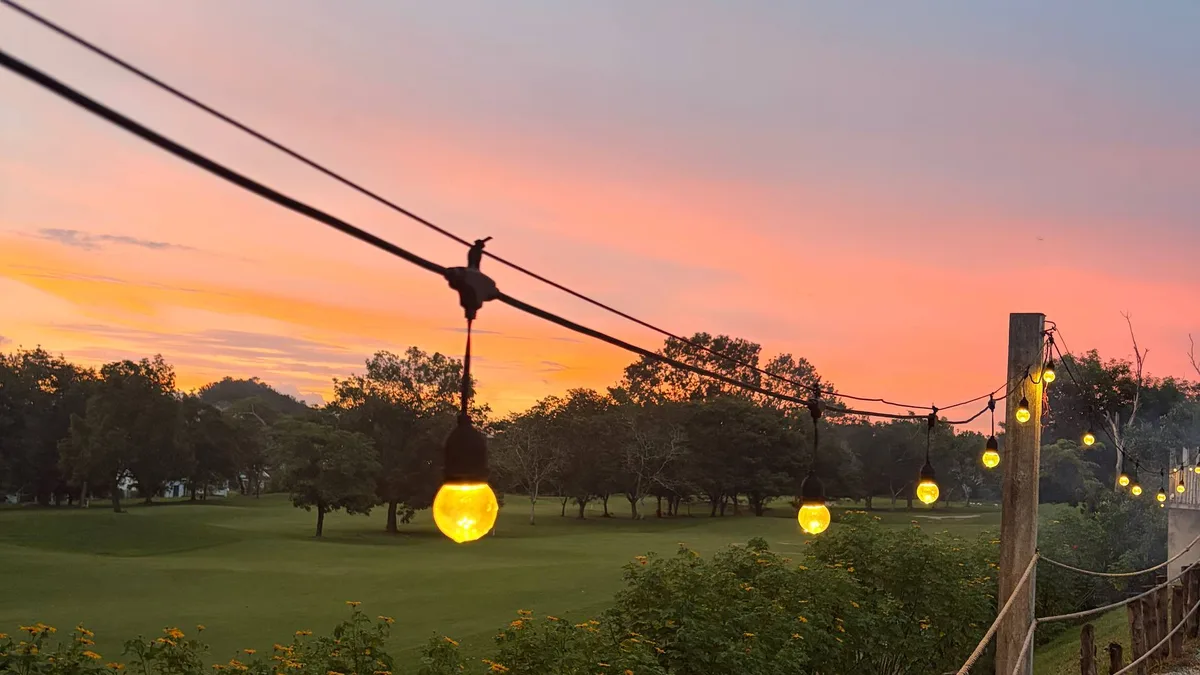 Matahari terbenam di padang golf Darulaman dengan lampu hiasan, pemandangan dari Sunset View